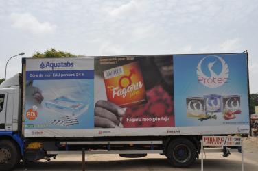 A truck advertises Aquatabs, Protec condoms, and Fagaru condoms.